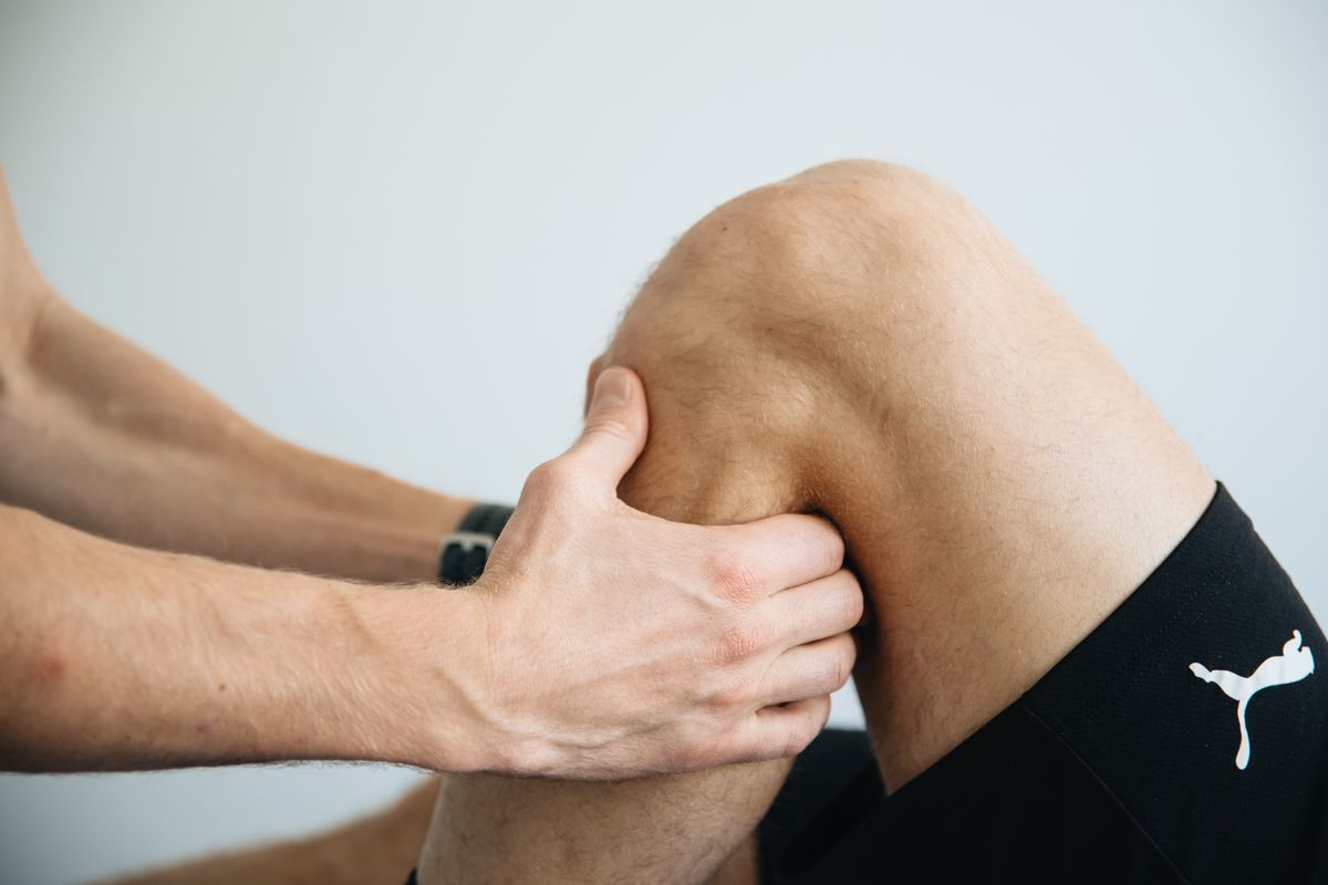 Lesión combinada de rodilla: fisioterapeuta valorando la rodilla de un paciente en camilla