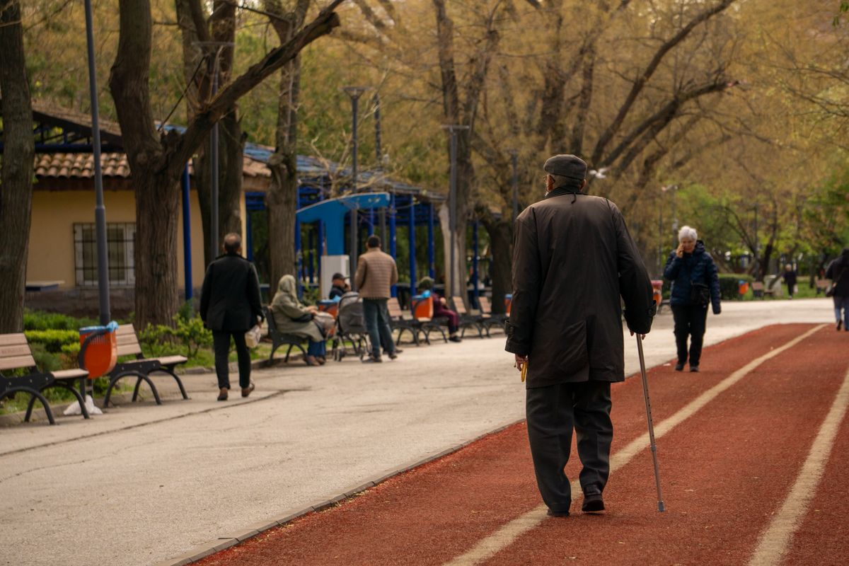 Masa muscular y función: persona mayor caminando con bastón por un parque
