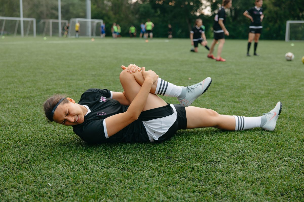 Rotura de isquiotibiales: futbolista en el suelo tras una lesión muscular durante un partido