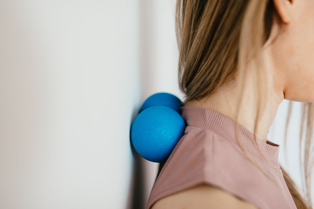 Mujer aliviando con una pelota los puntos dolorosos del cuello