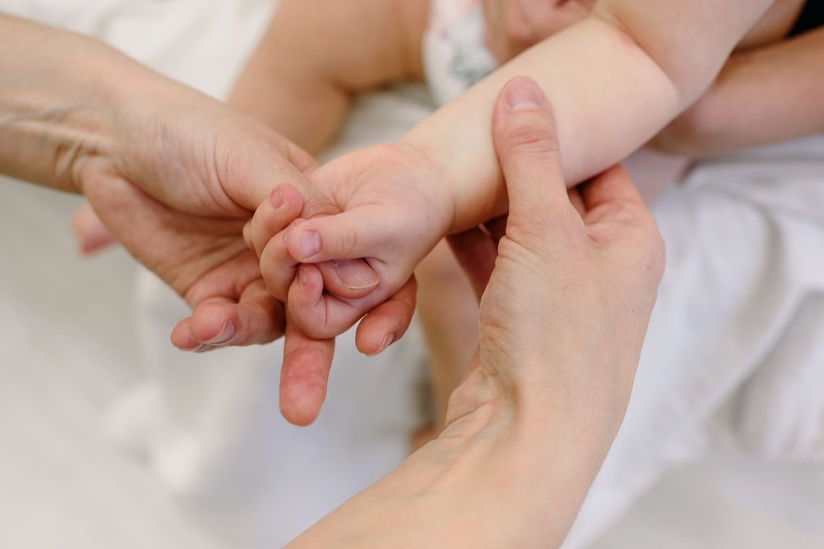Fisioterapia de bebés en Barcelona: manos de una fisioterapeuta sosteniendo los pies de un bebé