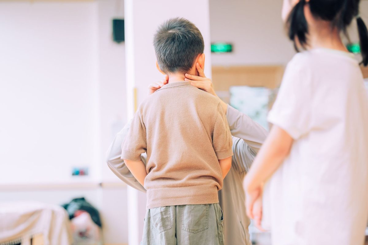 Osteopatía pediátrica en Barcelona: fisioterapeuta explorando con las manos el cuello y el hombro de un niño en la consulta